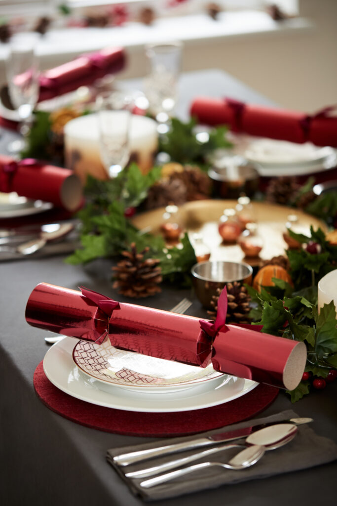 a red christmas cracker on a plate on a table set ready for christmas dinner