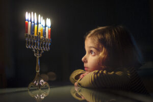 a young girl looking at a menorah